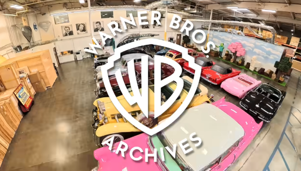 Interior view of the Warner Bros. Archives showcasing a variety of classic cars, featuring bright colors and unique designs, with the Warner Bros. logo prominently displayed.